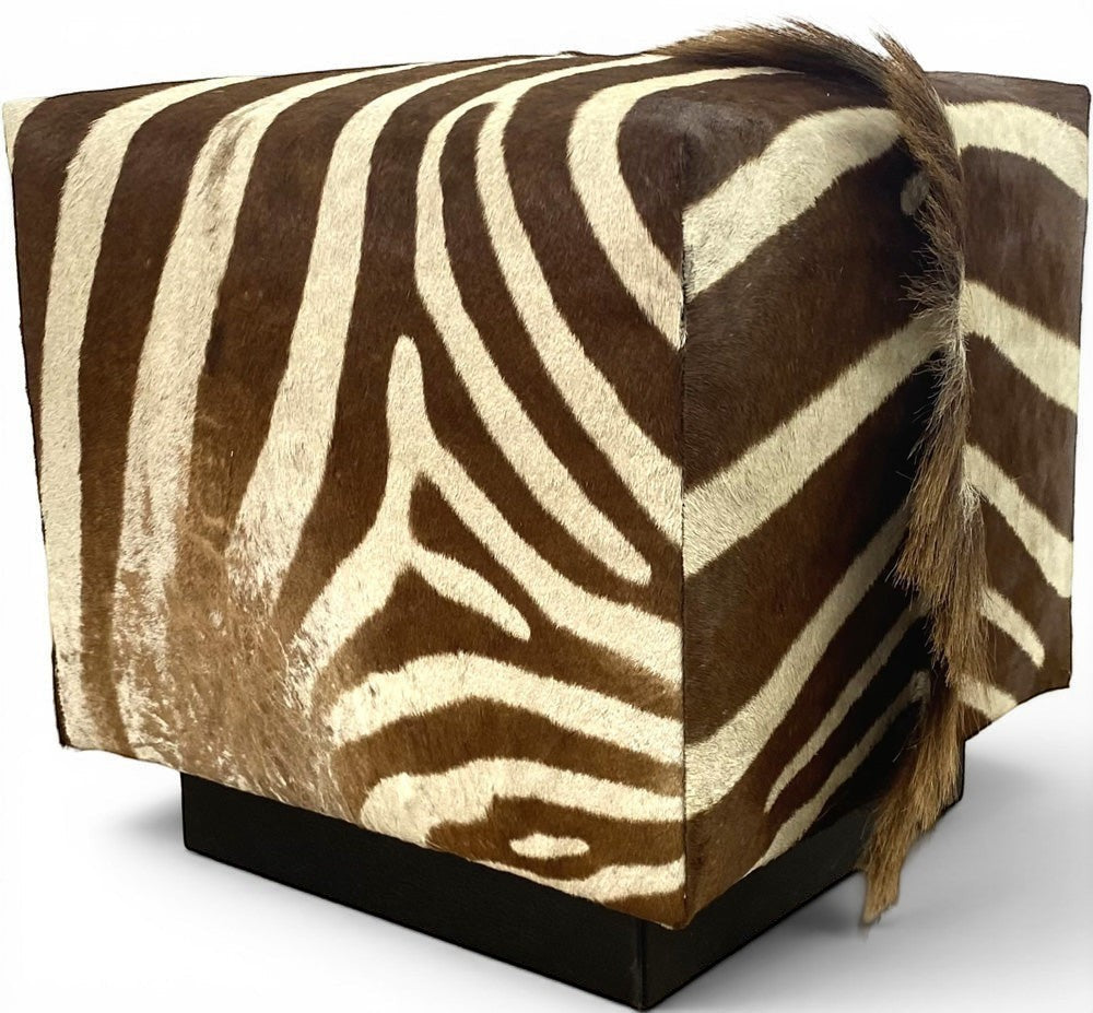 Pillowfina vintage zebra hide cube ottoman with natural brown and white striped fur and a decorative tail detail.
